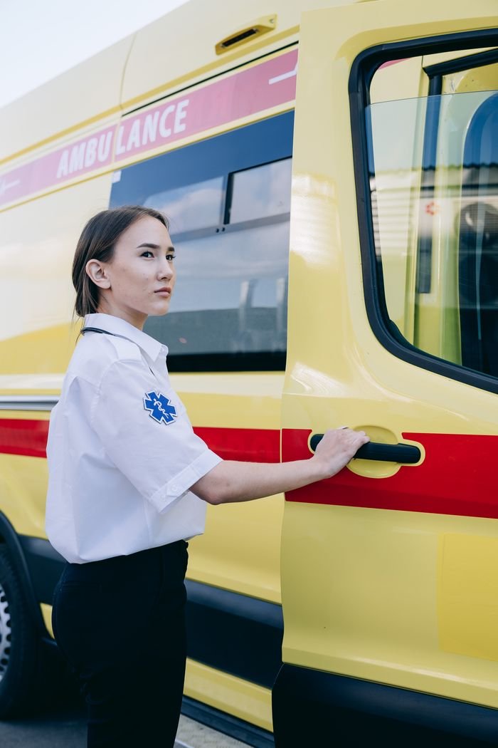 Crafting Captivating Headlines: Your awesome post title goes here Young female EMT standing by an ambulance, ready for emergency response.